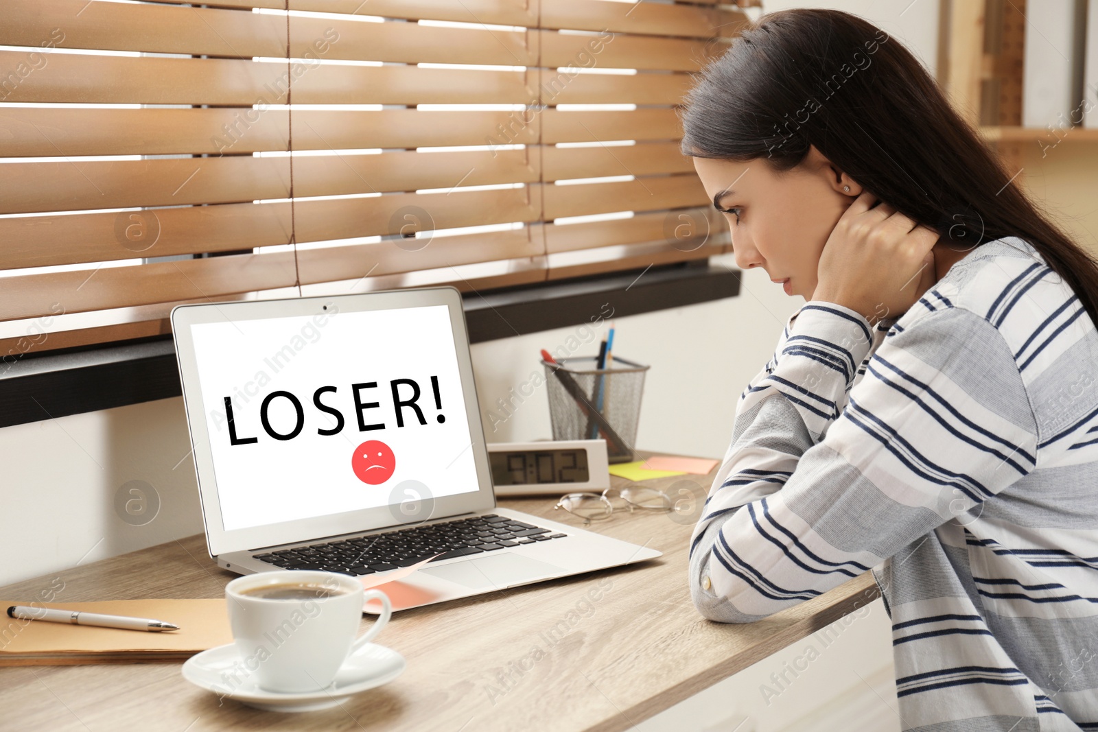 Image of Young woman using laptop at wooden table. Cyber bullying