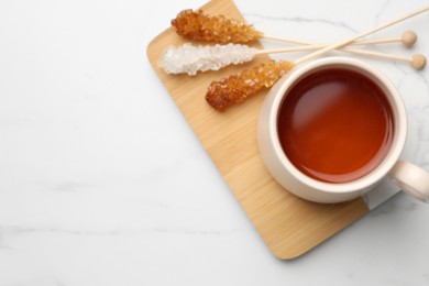 Photo of Sticks with sugar crystals served to tea on white table, top view. Space for text