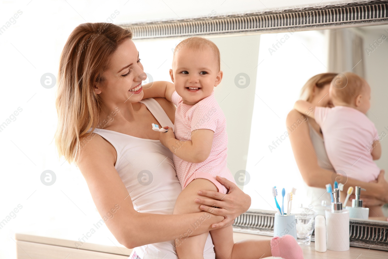 Photo of Woman holding daughter with toothbrush in bathroom. Space for text