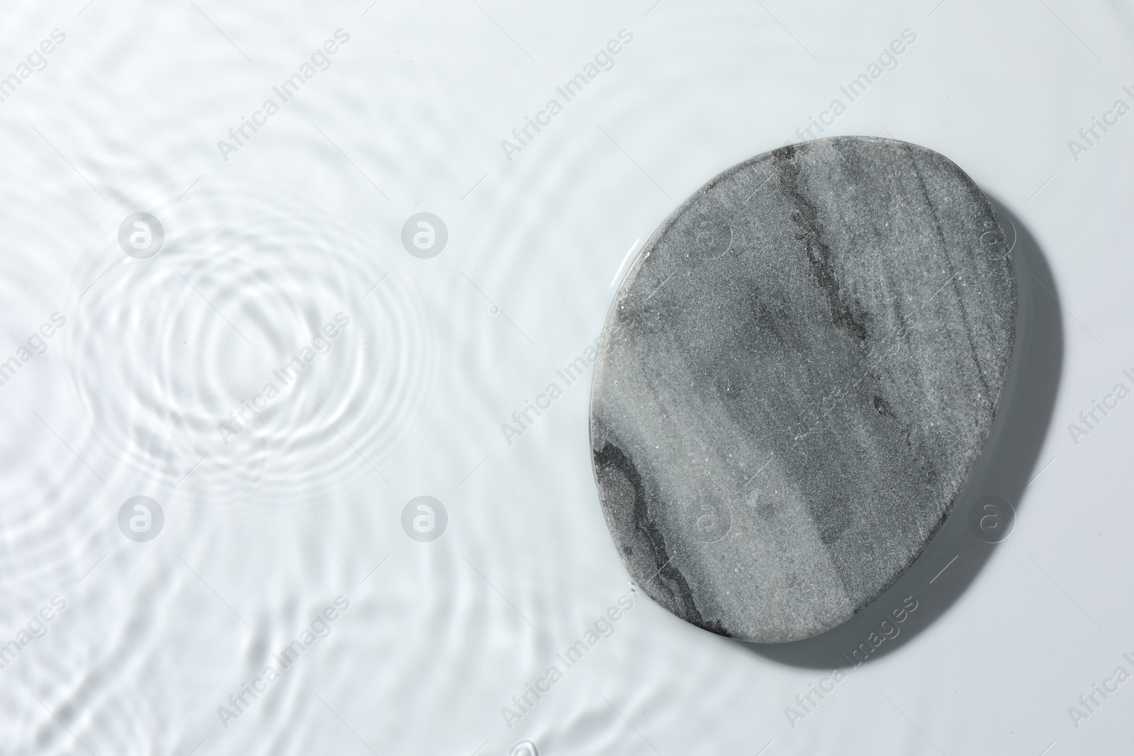 Photo of Presentation of product. Stone podium in water on white background, top view. Space for text