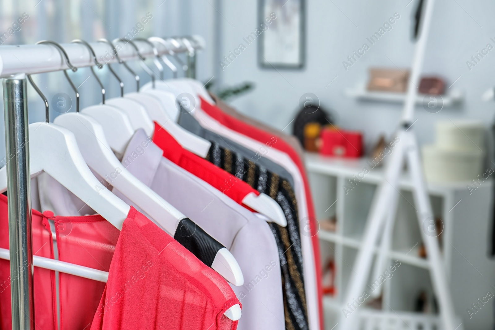 Photo of Stylish clothes hanging on wardrobe rack indoors, closeup. Space for text