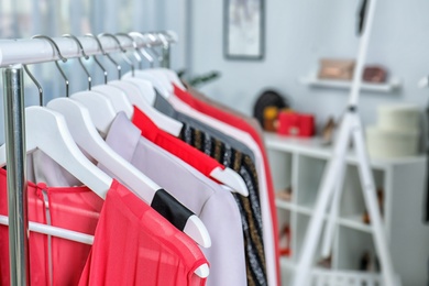 Stylish clothes hanging on wardrobe rack indoors, closeup. Space for text