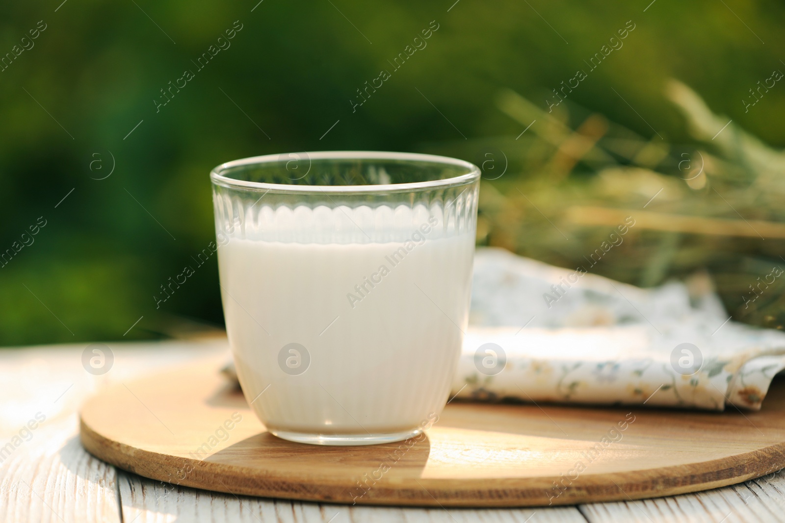 Photo of Glass of tasty fresh milk on white wooden table against blurred background