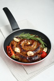 Photo of Delicious homemade sausage with garlic, tomato, rosemary and chili in frying pan on white table