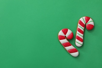 Photo of Christmas candy cane shaped gingerbread cookies on green background, flat lay. Space for text