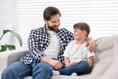 Photo of Happy dad and son spending time together on sofa at home