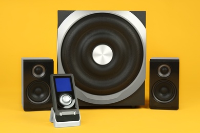 Modern powerful audio speaker system with remote on yellow background