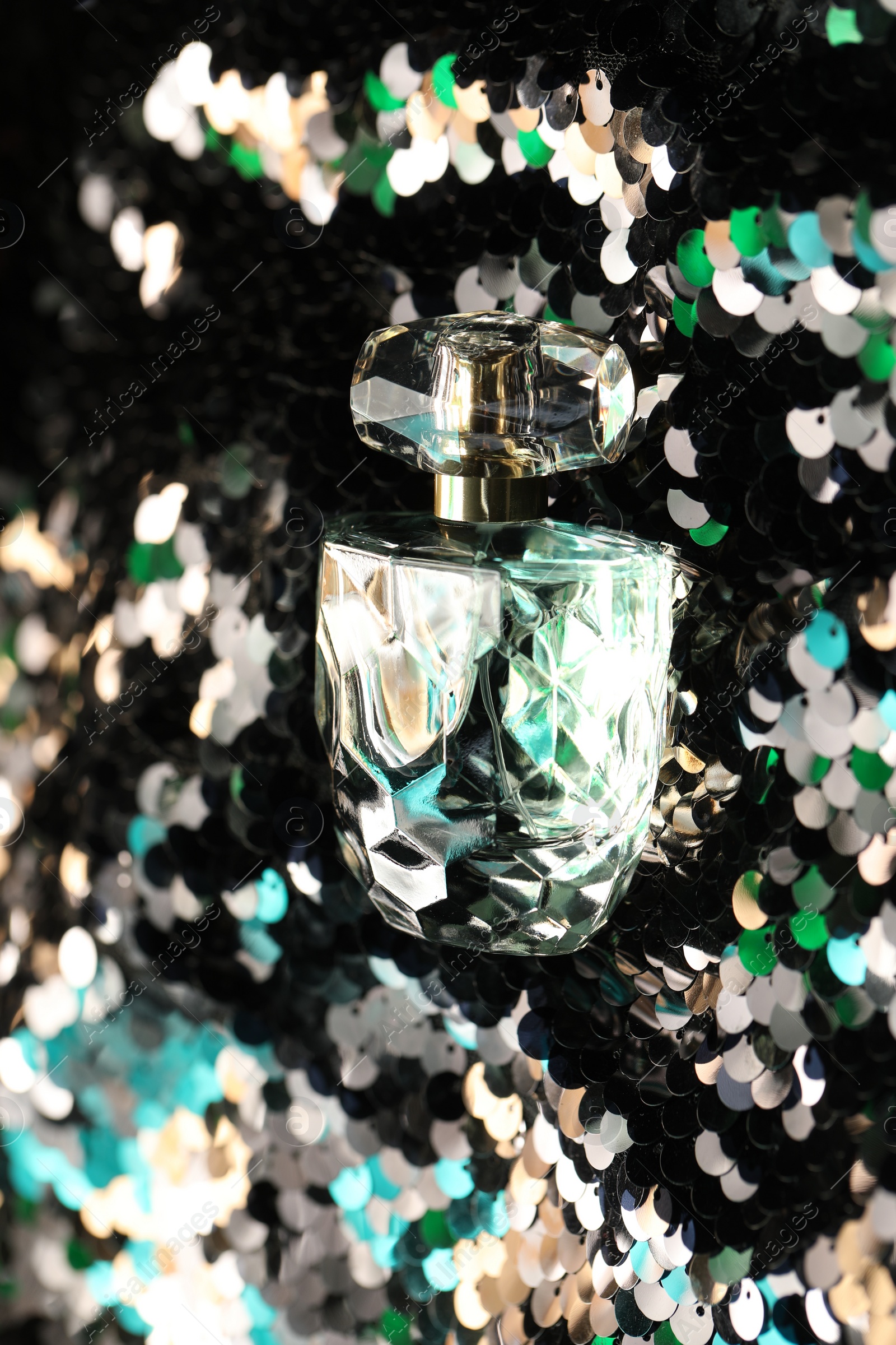 Photo of Luxury perfume in bottle on fabric with colorful sequins