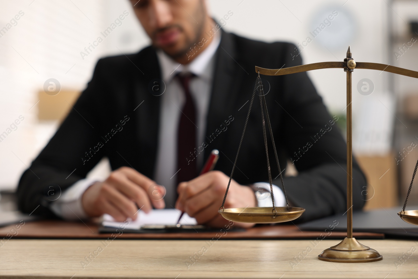 Photo of Lawyer working at table in office, focus on scales of justice