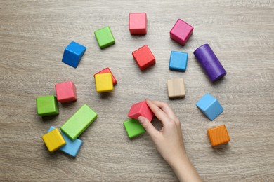 ABA therapist with colorful building blocks at wooden table, top view