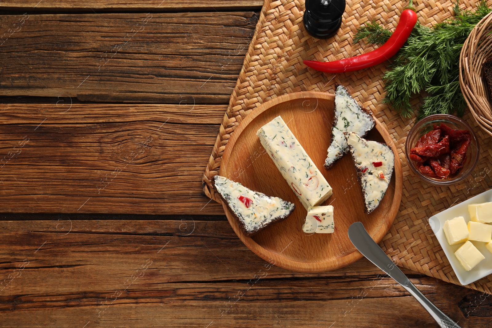 Photo of Tasty butter, dill, chili peppers and rye bread on wooden table, top view. Space for text