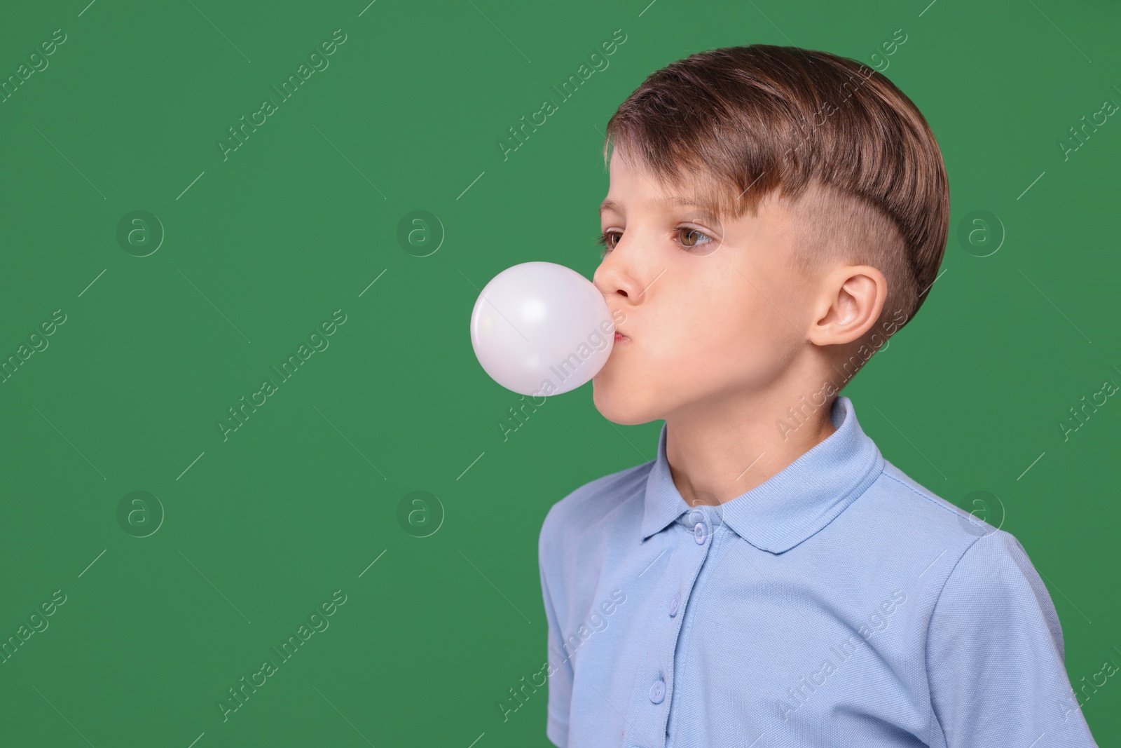 Photo of Boy blowing bubble gum on green background, space for text