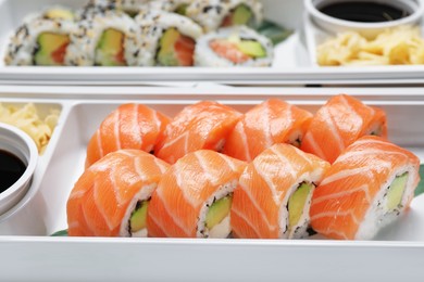 Photo of Delicious sushi rolls in plastic containers, closeup. Food delivery