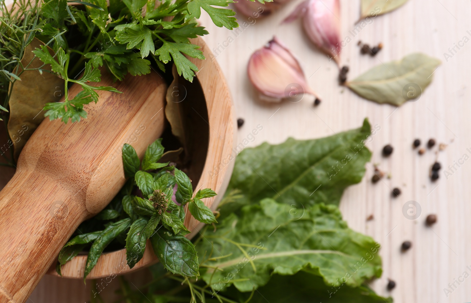 Photo of Mortar with pestle and different ingredients on wooden table, closeup