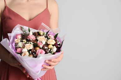 Woman with beautiful food bouquet on light grey background, closeup. Space for text