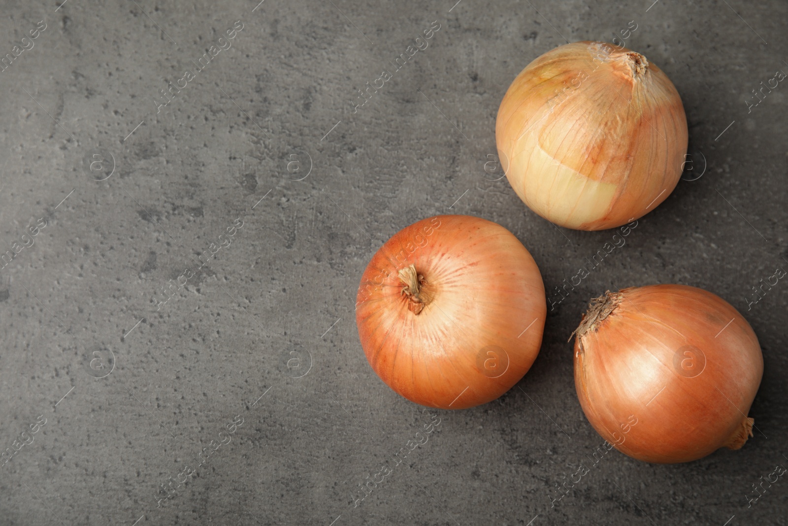 Photo of Ripe onions on grey table, flat lay with space for text