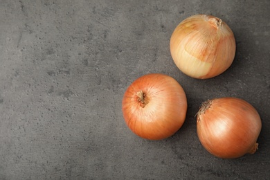 Ripe onions on grey table, flat lay with space for text