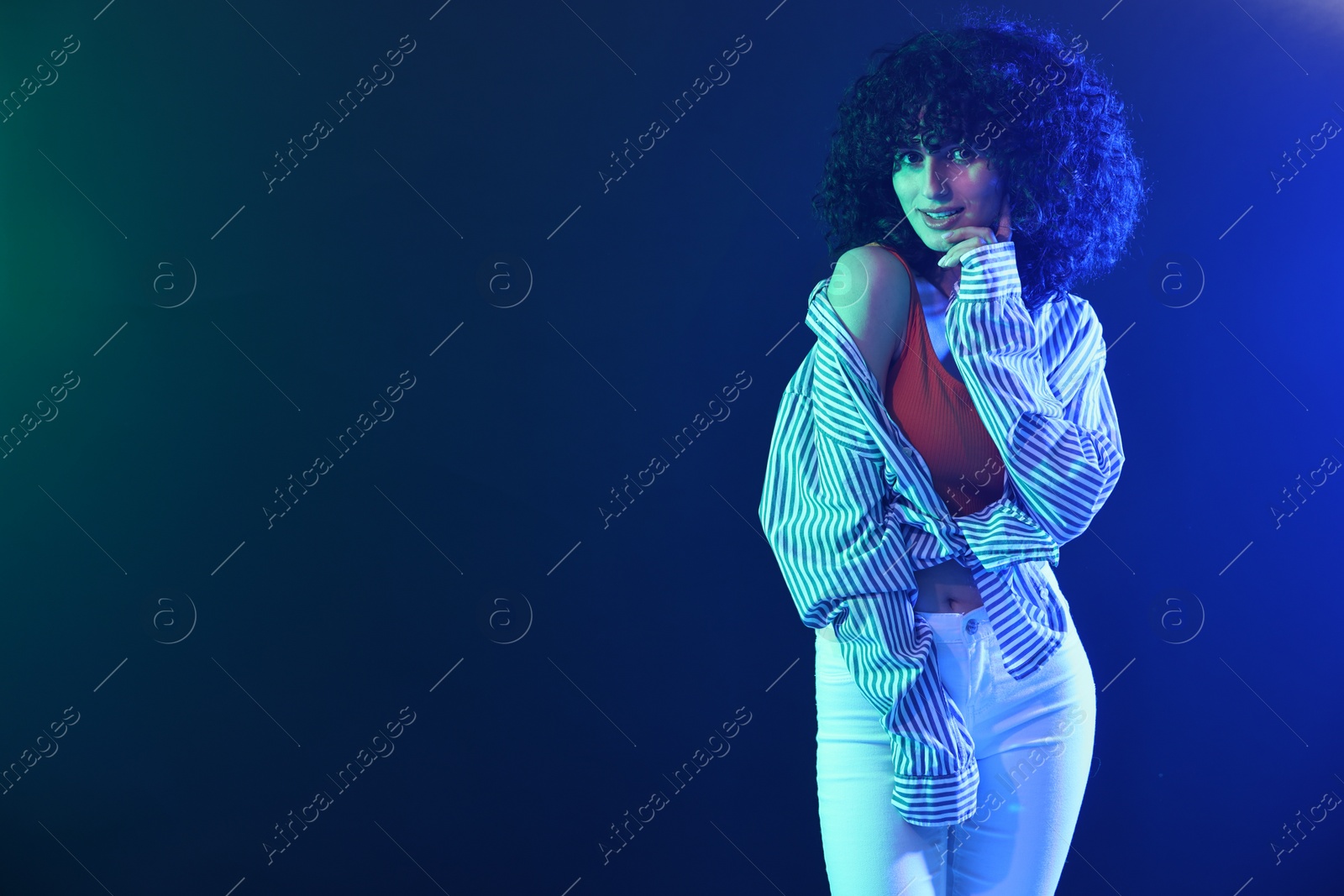 Photo of Beautiful young woman posing on color background in neon lights. Space for text