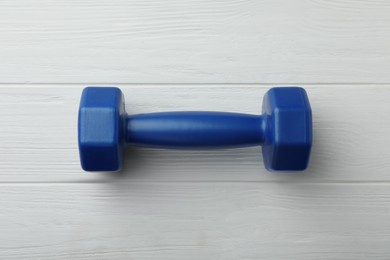 Photo of One blue dumbbell on white wooden table, top view