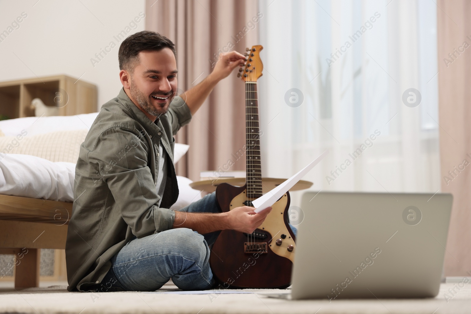 Photo of Music teacher tuning guitar while conducting online lesson at home. Time for hobby