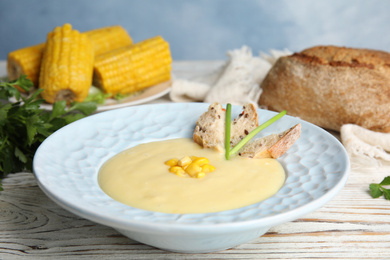Photo of Delicious corn cream soup served on white wooden table