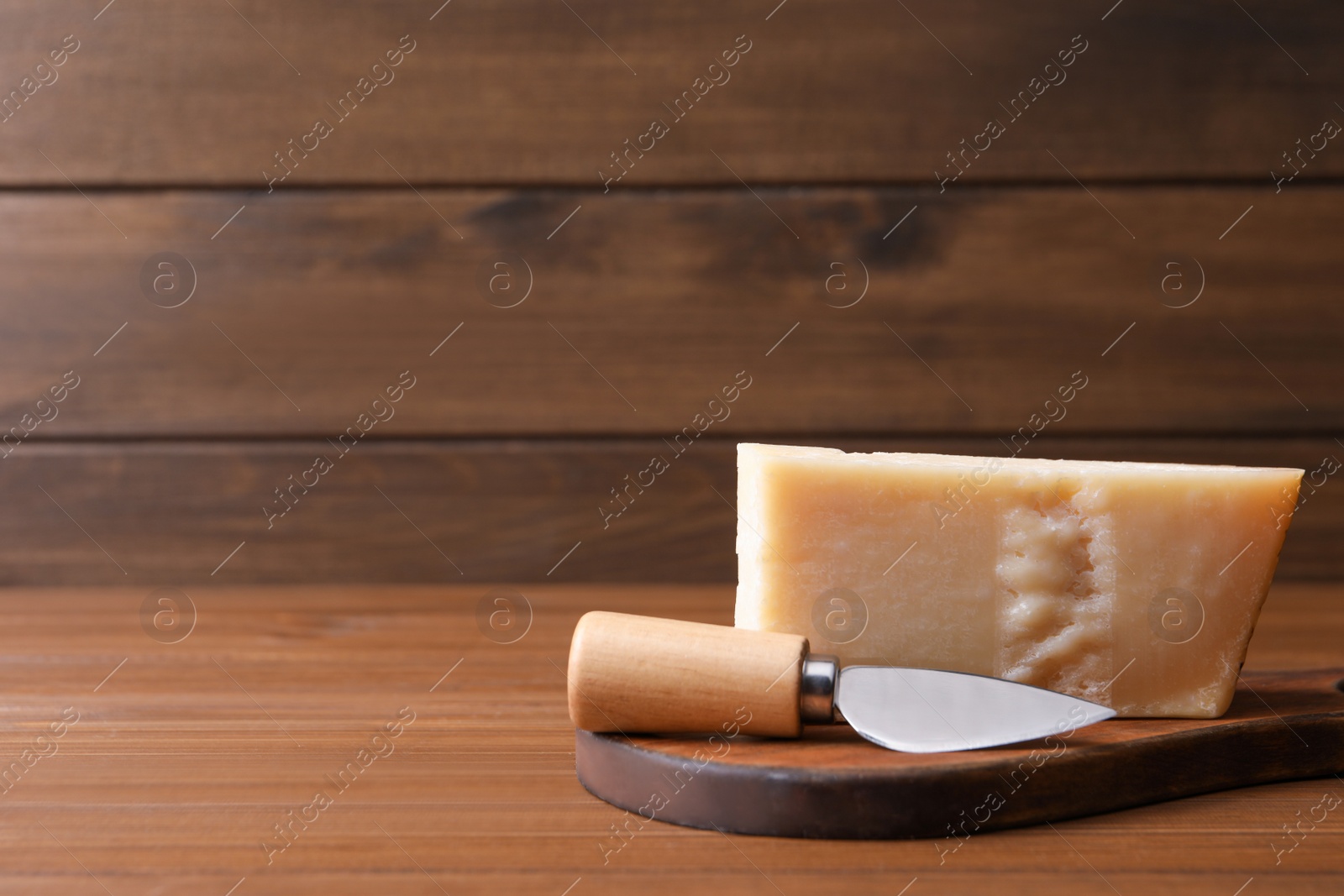 Photo of Delicious parmesan cheese with knife on wooden table. Space for text