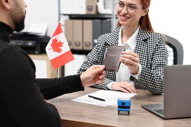 Immigration to Canada. Smiling embassy worker giving passport to man in office