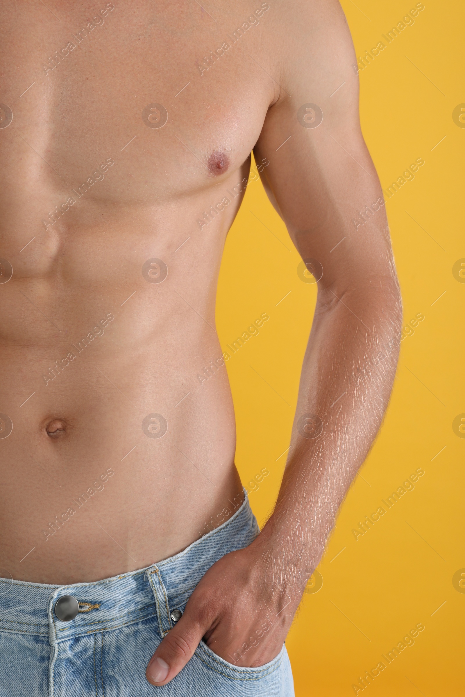 Photo of Shirtless man with slim body on yellow background, closeup