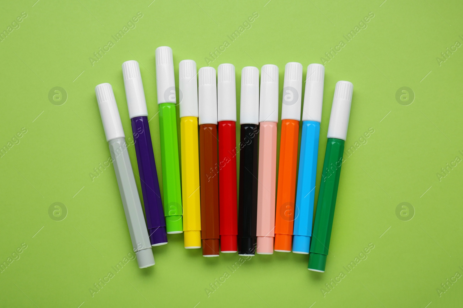 Photo of Many different colorful markers on light green background, flat lay