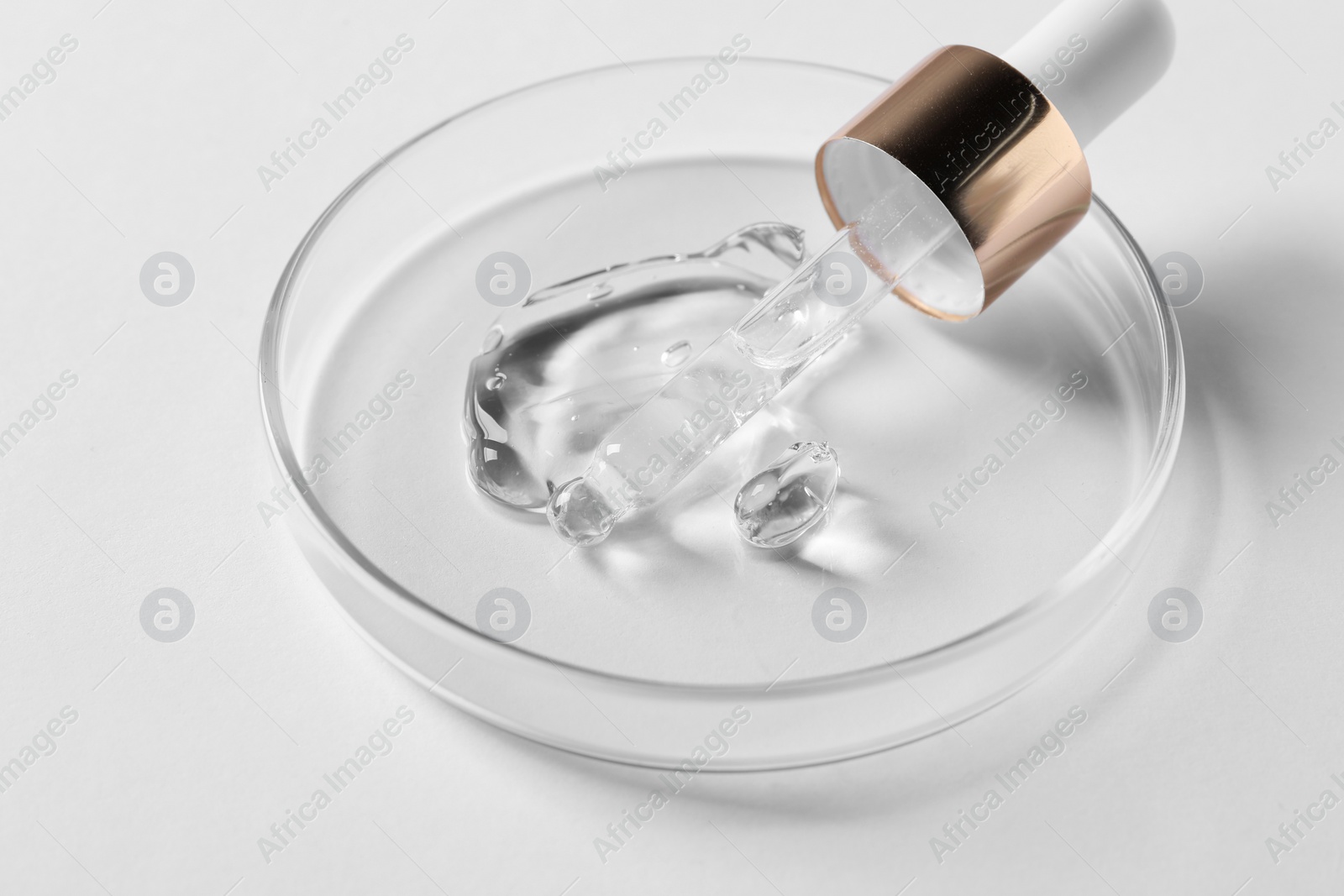 Photo of Petri dish with sample of cosmetic serum and pipette on white background, closeup