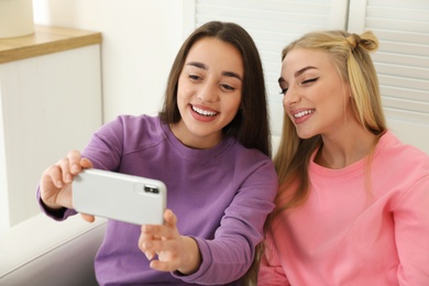 Photo of Young women laughing while taking selfie at home