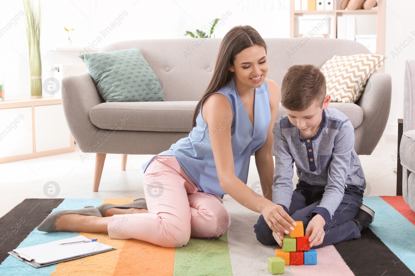 Photo of Child psychologist and boy playing with cubes in office