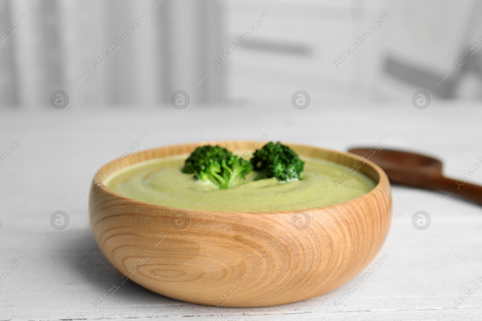 Photo of Delicious broccoli cream soup served on white wooden table