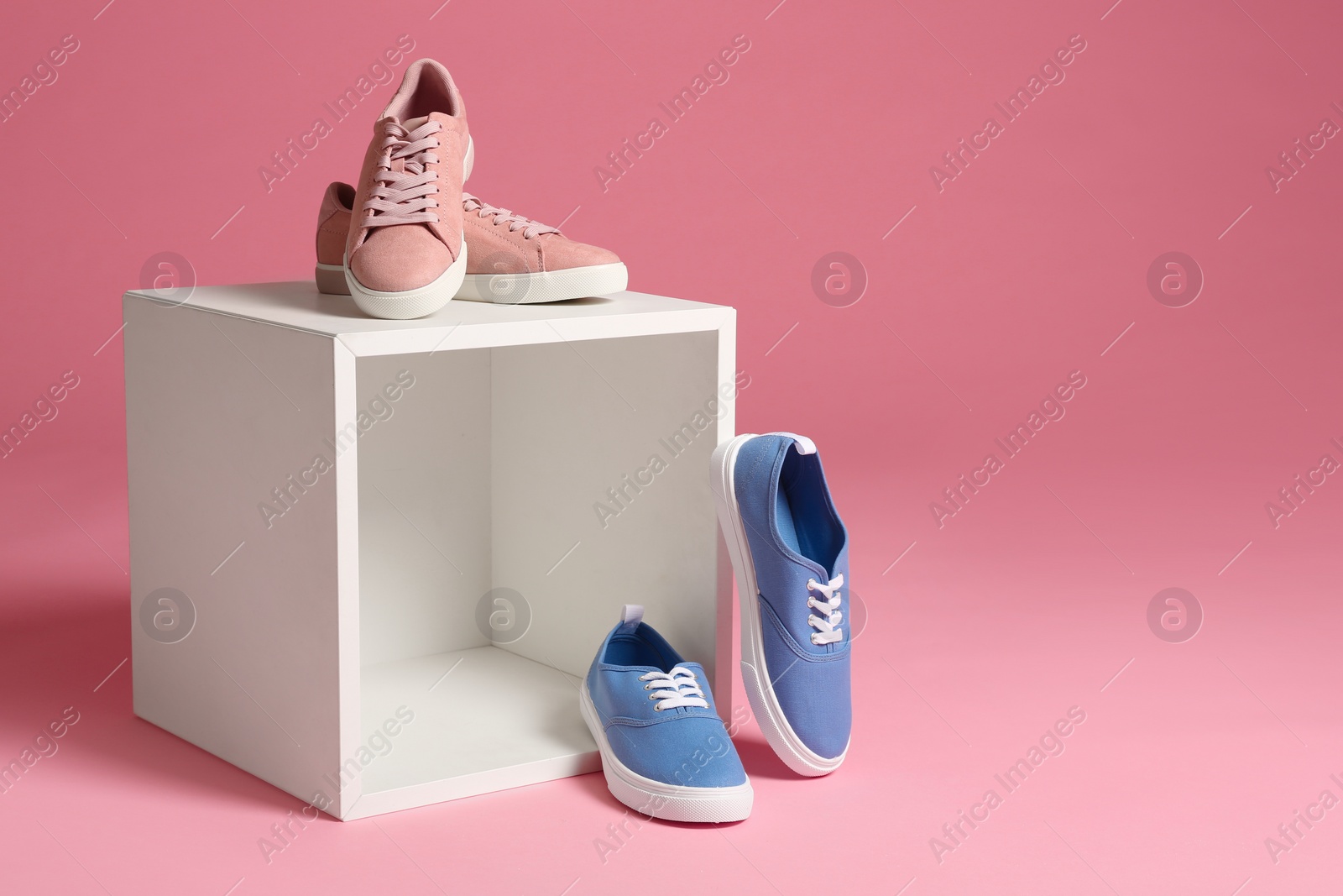 Photo of Different bright stylish shoes on decorative stand against color background. Space for text