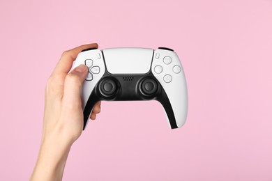 Woman with game controller on pink background, closeup