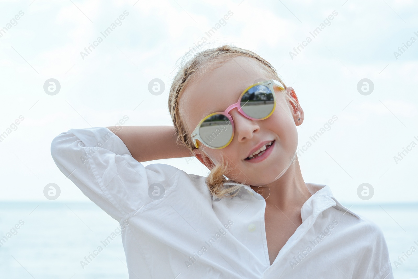 Photo of Little girl wearing sunglasses at beach on sunny day