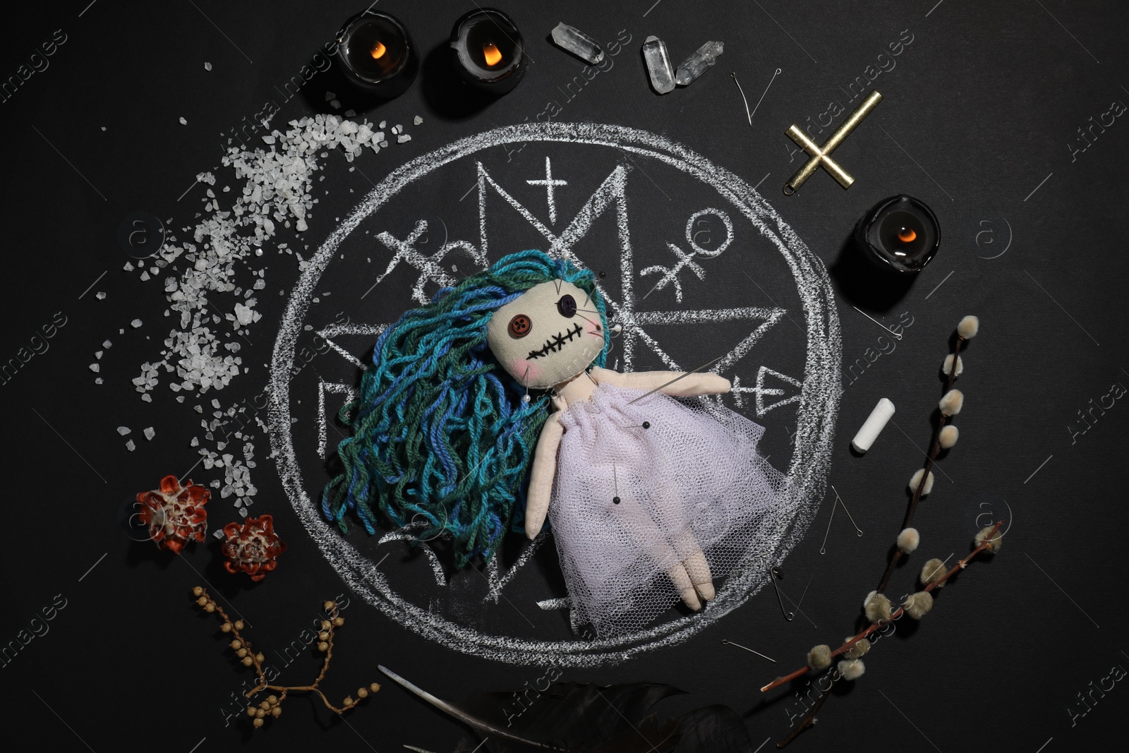Photo of Female voodoo doll with pins surrounded by ceremonial items on black background, flat lay