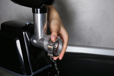 Woman washing electric meat grinder under kitchen sink, closeup. Space for text