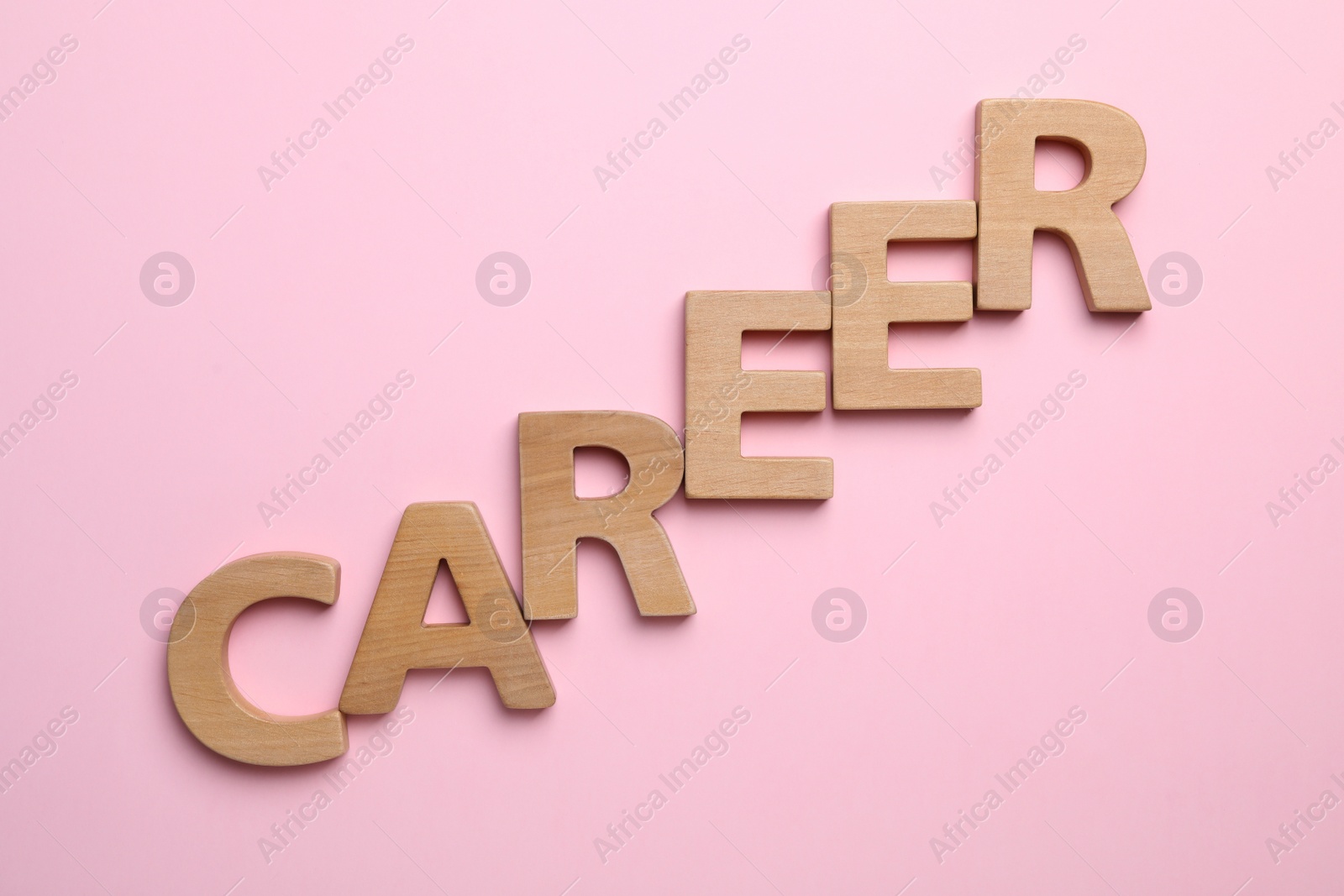 Photo of Word CAREER made with wooden letters on pink background, flat lay