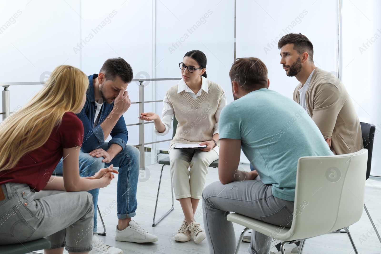 Photo of Psychotherapist working with group of drug addicted people at therapy session indoors