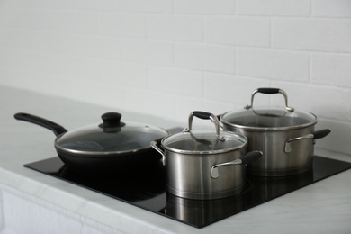 Saucepots and frying pan on induction stove in kitchen