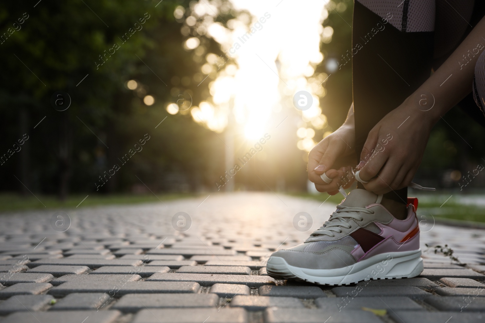 Photo of Woman tying shoelaces before morning run in park, closeup. Space for text