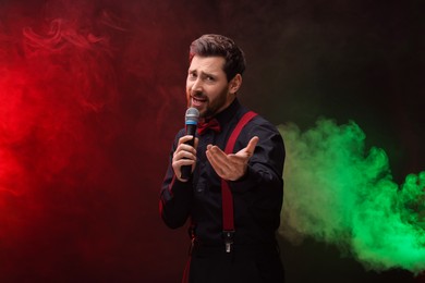 Emotional man with microphone singing in color lights