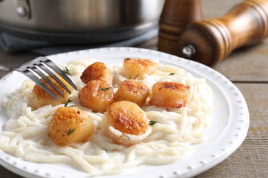 Photo of Delicious scallop pasta served on wooden table, closeup