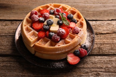 Photo of Tasty Belgian waffles with fresh berries, cheese and powdered sugar on wooden table, closeup