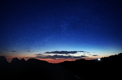 Image of Picturesque view of dawn sky with many stars and clouds over mountains