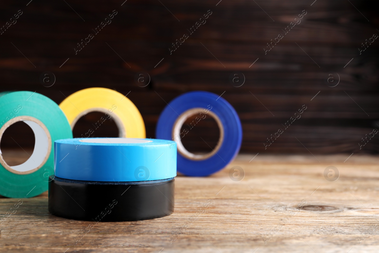 Photo of Colorful insulating tapes on wooden table, space for text