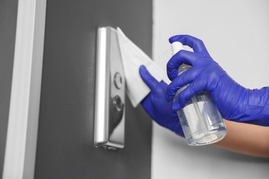 Photo of Woman wiping elevator call panel with detergent and paper napkin, closeup