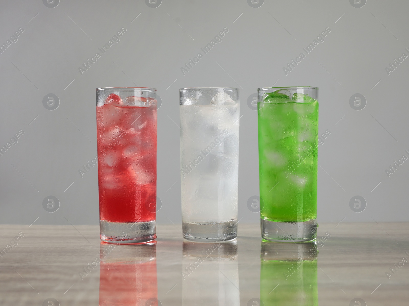 Photo of Delicious refreshing drinks in glasses on grey table