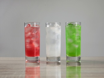 Delicious refreshing drinks in glasses on grey table